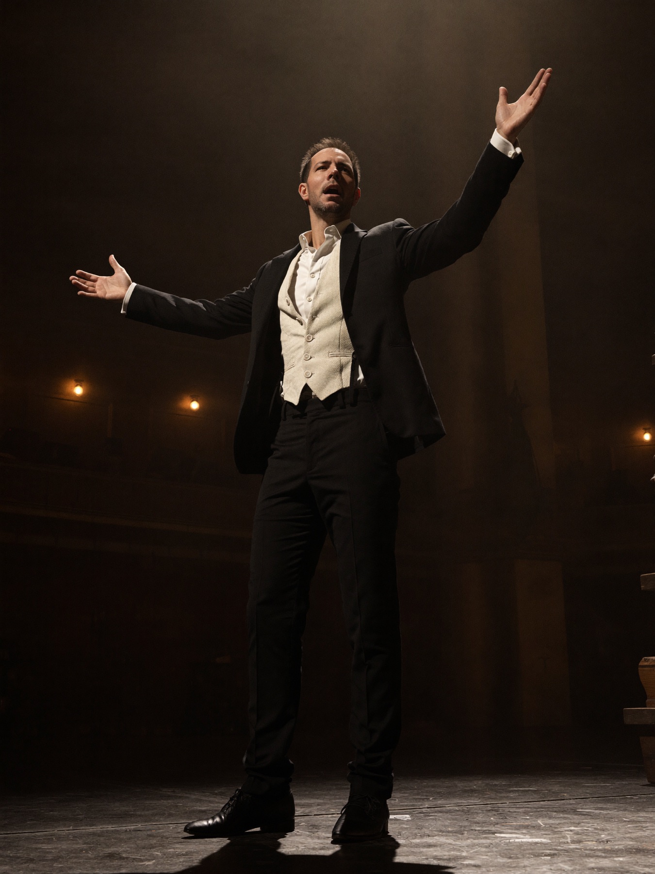 Derek Rue performing on stage with his arms extended.